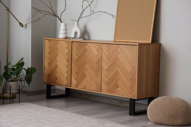 Vazolarla ahşap büfe ve oturma odasındaki gri duvarın yanında boş çerçeve.