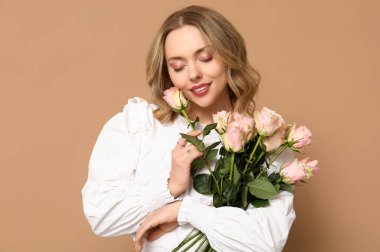 Kahverengi arka planda gül buketi olan güzel genç bir kadın.