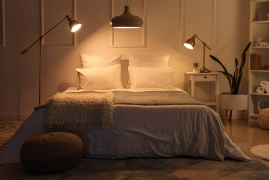 Rahat yatağın üzerinde yumuşak battaniyeler, hasır puf ve geceleri parlayan lambalar olan rahat yatak odasının içi.