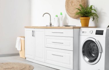 Lavabo, çamaşır makinesi ve çamaşır sepetinin olduğu odanın içi.