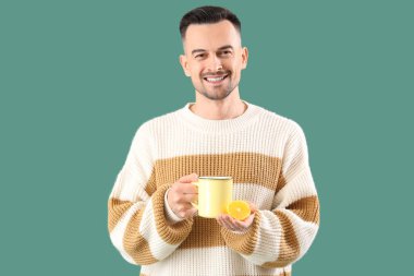 Yeşil arka planda bir fincan çayı olan genç adam.