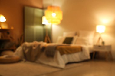 Yatak odasının bulanık görüntüsü, yatakta ekose kumaşlar ve gece lambaları.