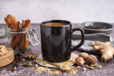 Masada farklı baharatlar olan bir fincan lezzetli masala çayı, yakın plan.