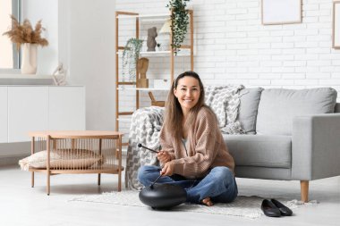 Güzel, olgun bir kadın evde halıda glukofon çalıyor.