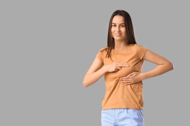 Genç kadın göğüslerini ışık arka plan üzerinde kontrol. Kanser farkındalık kavramı