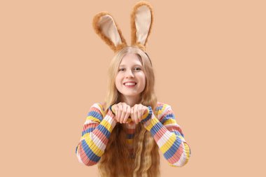 Bej arka planda Paskalya tavşanı kulaklı genç bir kız.