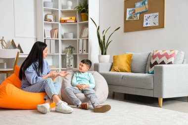 Kadın psikolog ofiste küçük bir çocukla konuşuyor.