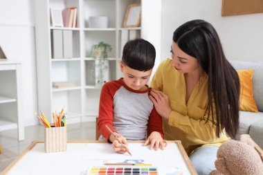 Ofiste resim çizen küçük bir çocukla kadın psikolog.