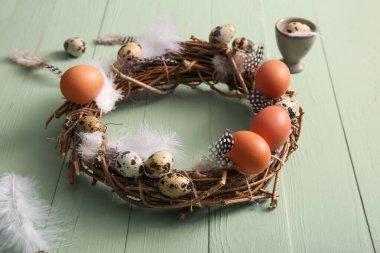 Yeşil ahşap arka planda yumurta ve tüylü güzel Paskalya çelengi