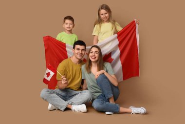 Kahverengi arka planda Kanada bayrakları olan mutlu bir aile.
