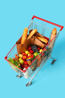 Mavi arka planda ödeme terminali olan tam alışveriş arabası.