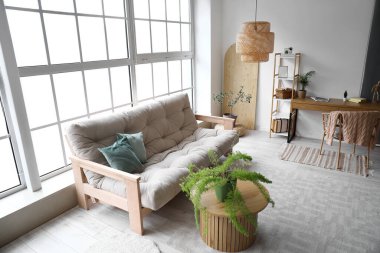 Oturma odasındaki panoramik pencerelerin yanında kanepesi olan modern bir iç mekan.