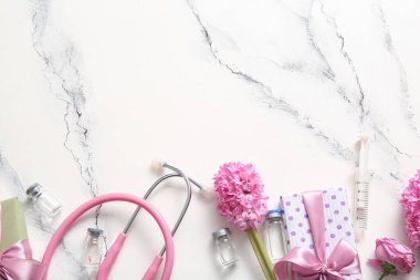 Çiçekli steteskop, hediye kutusu ve beyaz grunge arka planda Uluslararası Hemşireler Günü için ampuller