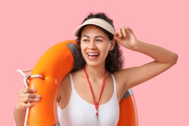 Pembe arka planda halka şamandırası olan güzel, mutlu, Afro-Amerikan kadın cankurtaran.