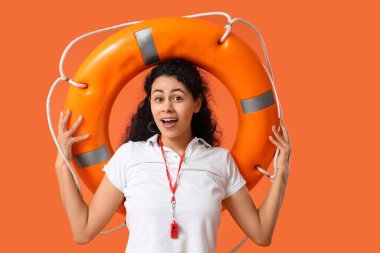 Turuncu arka planda halka şamandırası olan Afro-Amerikan kadın cankurtaran.