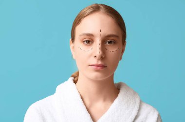 Yüzünde mavi arka planda izler olan genç bir kadın. Blepharoplasty konsepti