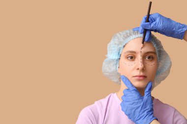 Plastik cerrah, kadın yüzüne kahverengi arka planda izler uyguluyor. Blepharoplasty konsepti