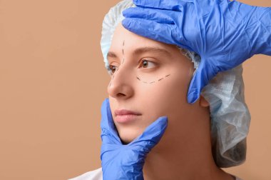 Plastik cerrah kahverengi arka planda kadının yüzünü inceliyor, yakın plan. Blepharoplasty konsepti