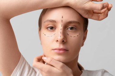 Yüzünde gri arka planda izler olan genç bir kadın, yakın plan. Blepharoplasty konsepti