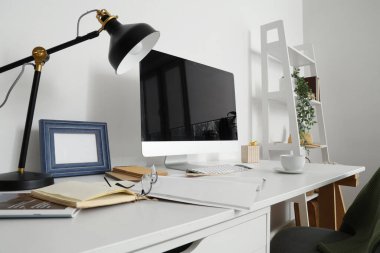 Ofisinde bilgisayar, lamba ve bardak olan modern işyeri