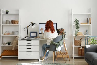 Işık ofisindeki şık işyerinin yanında oturan genç kadın.