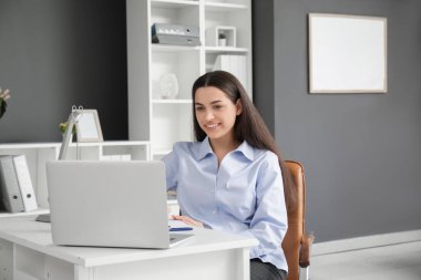 Ofisteki masada dizüstü bilgisayarla çalışan güzel bir iş kadını.