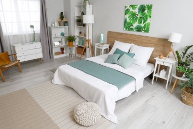 Yatak odasının içi yumuşak yatak, lambalar, raf üniteleri ve komodinlerle dolu.