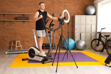 Spor salonunda eliptik antrenörle egzersiz yaparken çekilmiş spor videosu.