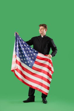 Yeşil arka planda Amerikan bayrağı taşıyan erkek rahip.