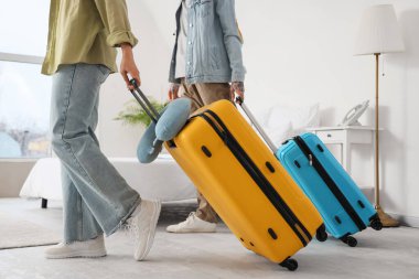 Otel odasında bavulları olan birkaç turist dolaşıyor.