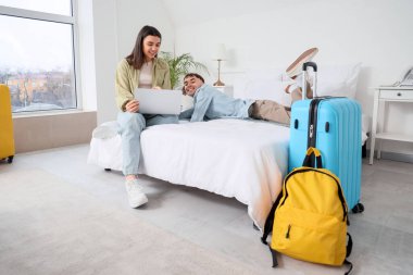 Otel odasında dizüstü bilgisayar kullanan iki turist.