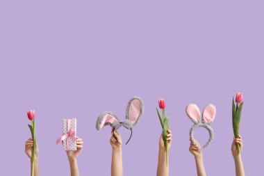 Laleli kadın eller, hediye ve menekşe arka planda tavşan kulaklıkları. Paskalya konsepti.