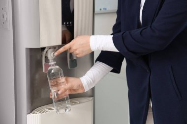 Plastik şişeyi soğutucudan filtreli suyla dolduran kadın.