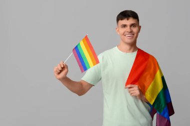 Gri arka planda LGBT bayrakları olan yakışıklı genç adam.