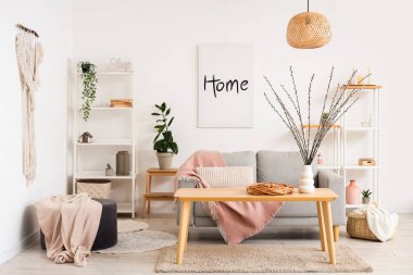 Kanepe ve vazoda söğüt dallarıyla aydınlık oturma odasının içinde.