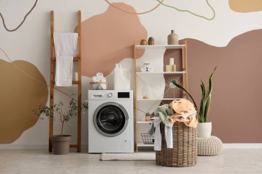 Çamaşır makinesi, sepeti ve raf ünitesi olan çamaşır odasının içi.