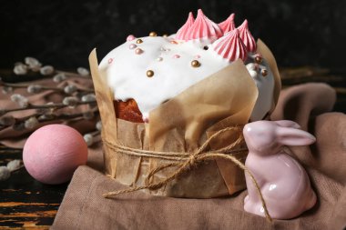 Yumurtalı tatlı Paskalya pastası, söğüt dalları ve siyah ahşap masada oyuncak tavşan.