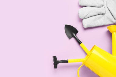 Leylak arka planında bahçe aletleri, eldiven ve sulama kutusu