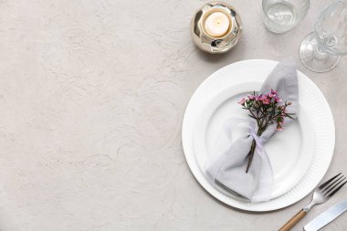 Gri arkaplanda yanan mum ve güzel çiçekli masa ayarı