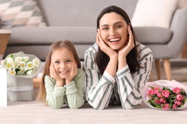 Mutlu bir anne, tatlı küçük kızı ve evde yerde yatan laleleri.
