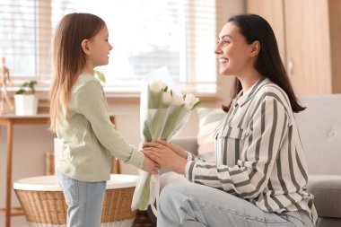Mutlu anne evde küçük tatlı kızından lale alıyor.