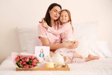 Mutlu bir anne ve küçük tatlı kızı yatak odasında sarılıyorlar.