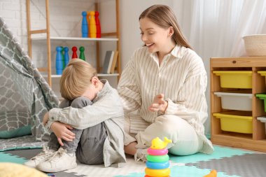 Ofiste stresli küçük bir çocukla çalışan kadın psikolog. Dünya Otizm Farkındalık Günü