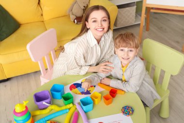 Kadın psikolog ve ofiste masada oynayan küçük bir çocuk. Dünya Otizm Farkındalık Günü