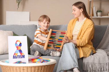 Kadın psikolog ve küçük çocuk ofiste abaküs ile oynuyorlar. Dünya Otizm Farkındalık Günü