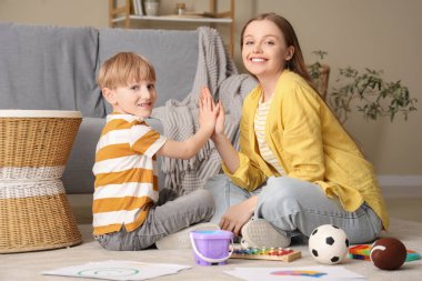 Kadın psikolog ve küçük çocuk ofiste birbirlerine beşlik çakıyorlar. Dünya Otizm Farkındalık Günü