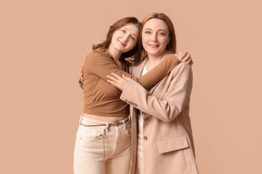 Güzel olgun bir kadın ve kızı kahverengi arka planda sarılıyor. Anneler Günü kutlaması