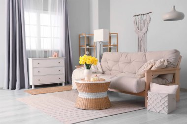 Kanepesi, çekmeceleri, sehpası ve narsisli çiçekleri olan şık bir oturma odası.