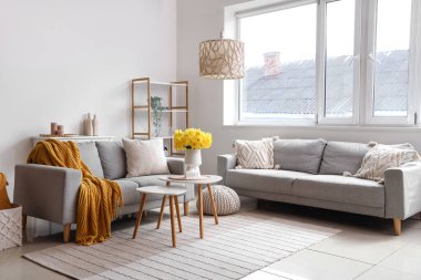 İçinde kanepeler, narsisli çiçekler ve kahve masası olan güzel bir oturma odası.