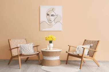 Bej oturma odasının içinde koltuklar, narsisli çiçekler ve kahve masası.